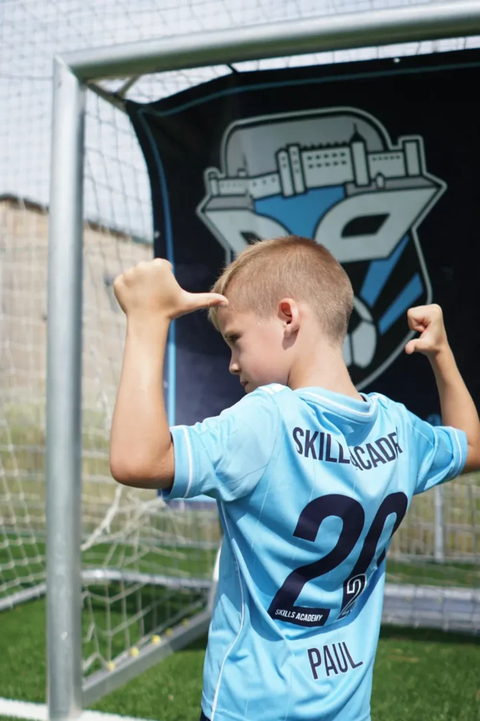 Junger Spieler im Skills-Academy-Trikot zeigt mit der Hand an den Kopf – kognitives Training