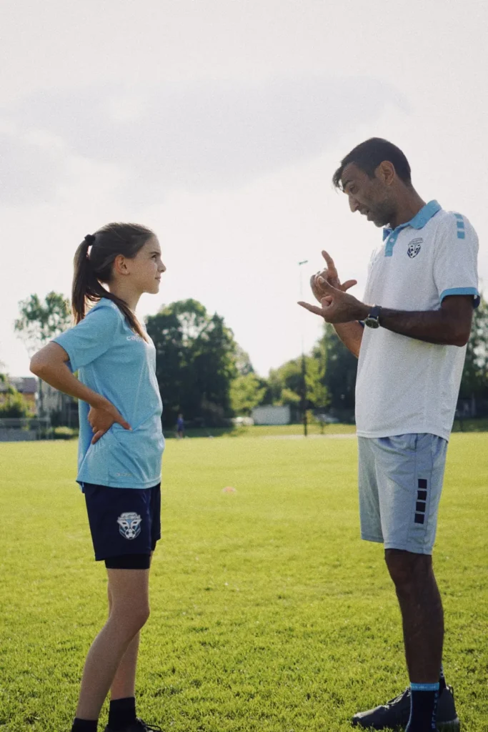 Trainerin im Gespräch mit Kindern auf dem Trainingsplatz